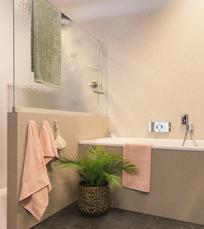 Badkamer met ligbad en douche, gescheiden door een stijlvolle glazen wand van kathedraalglas voor extra privacy.
