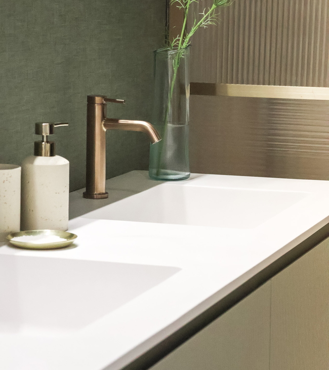 Een saliegroen badkamermeubel met ribbels van Vika gecombineerd met een bronzen wastafelkraan van Hansgrohe