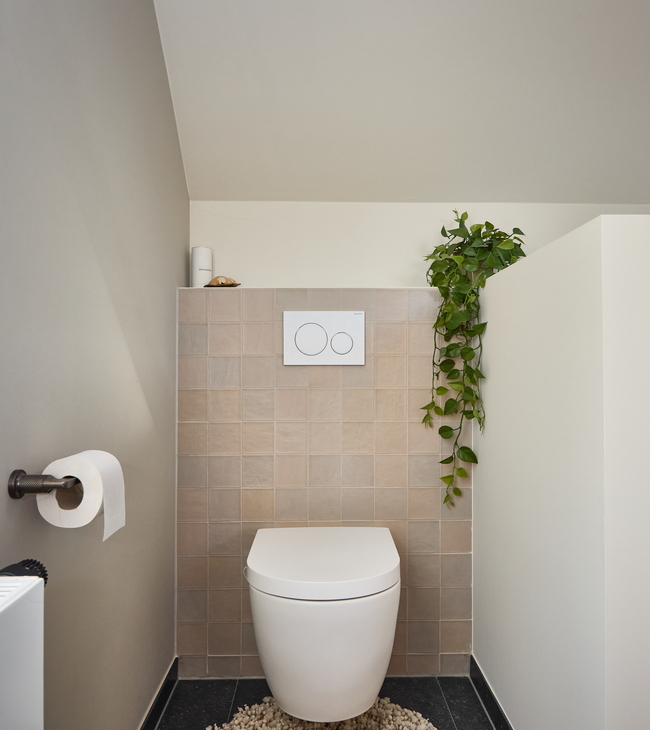 Strak afgewerkt toilet met beige wandtegels en modern hangtoilet als onderdeel van een complete badkamer renovatie.