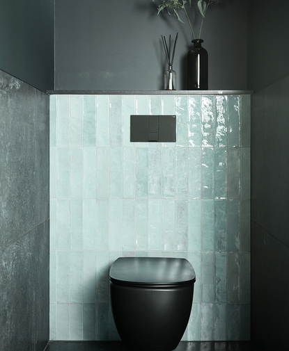 Modern toilet met zwarte pot, groene tegels op de achterwand en donkere muren voor een stijlvol contrast.